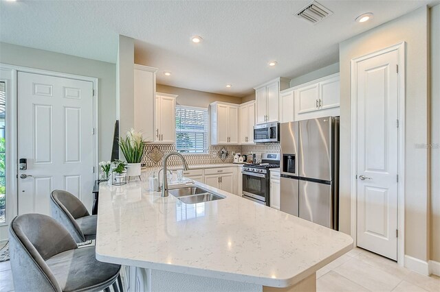 kitchen featuring sink, kitchen peninsula, stainless steel appliances, a breakfast bar area, and light stone countertops