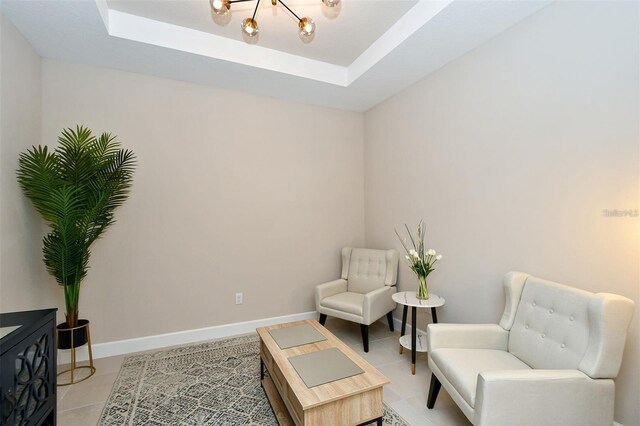 living area featuring a chandelier, a tray ceiling, and light tile patterned flooring