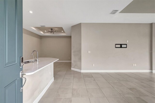 entrance foyer featuring light tile patterned floors, a raised ceiling, and sink