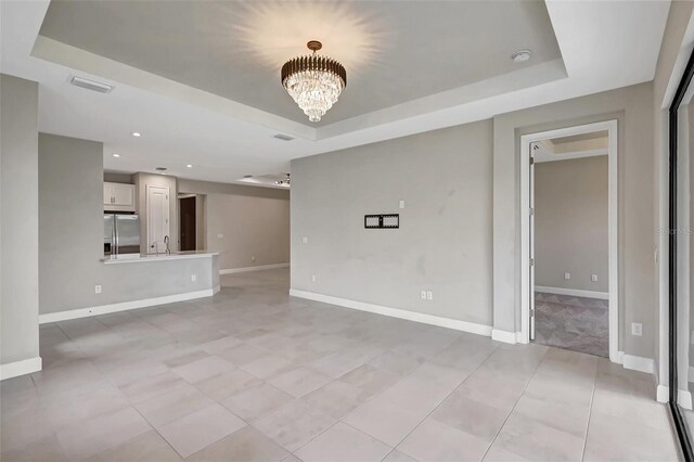 unfurnished living room with a chandelier and a raised ceiling