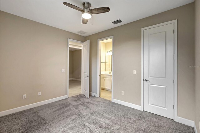 unfurnished bedroom with connected bathroom, ceiling fan, and light colored carpet