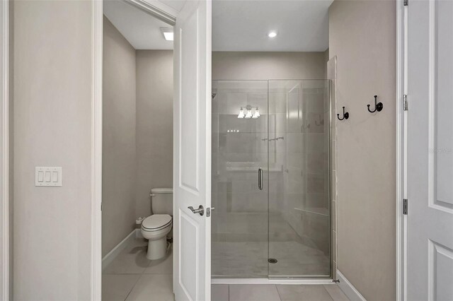 bathroom with tile patterned flooring, toilet, and an enclosed shower