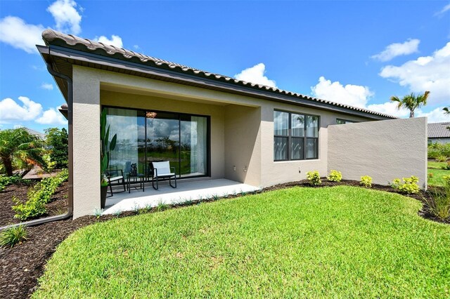 back of property with a lawn and a patio area