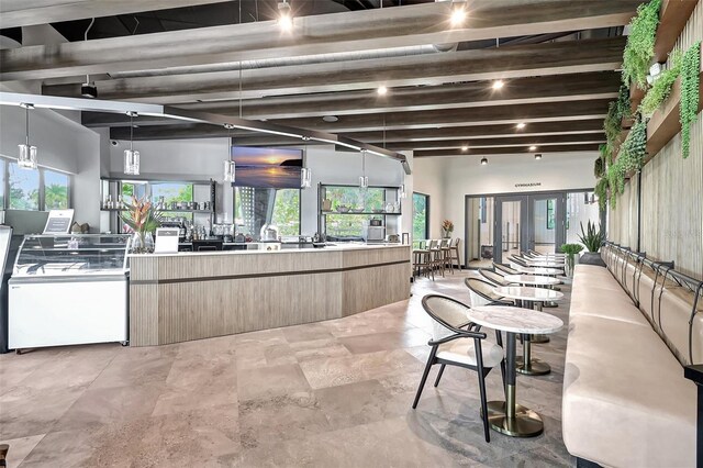 interior space featuring beam ceiling, light brown cabinets, and decorative light fixtures