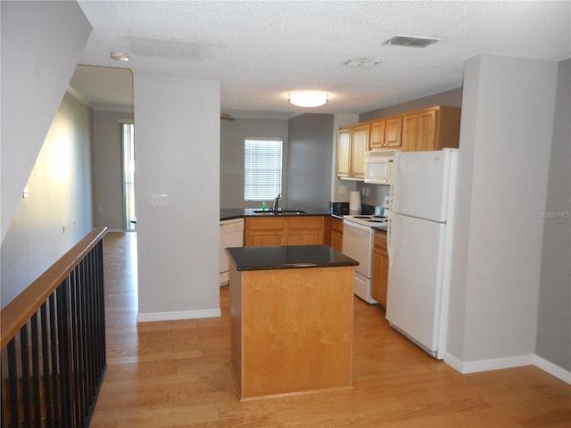 kitchen featuring white appliances, sink, light hardwood / wood-style flooring, a textured ceiling, and a kitchen island