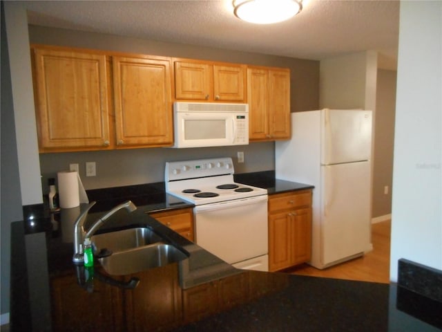 kitchen with light wood-type flooring, a textured ceiling, white appliances, and sink