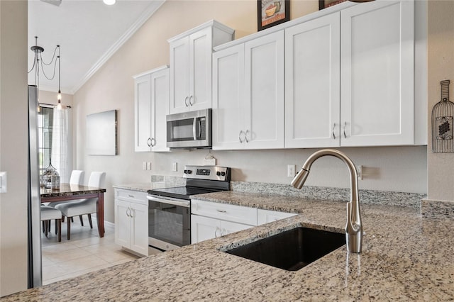 kitchen featuring ornamental molding, white cabinetry, vaulted ceiling, sink, and appliances with stainless steel finishes