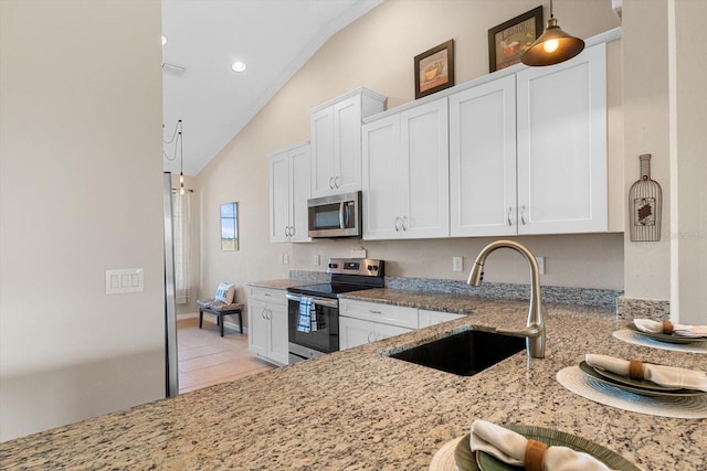 kitchen featuring stainless steel appliances, white cabinets, vaulted ceiling, a sink, and light stone countertops