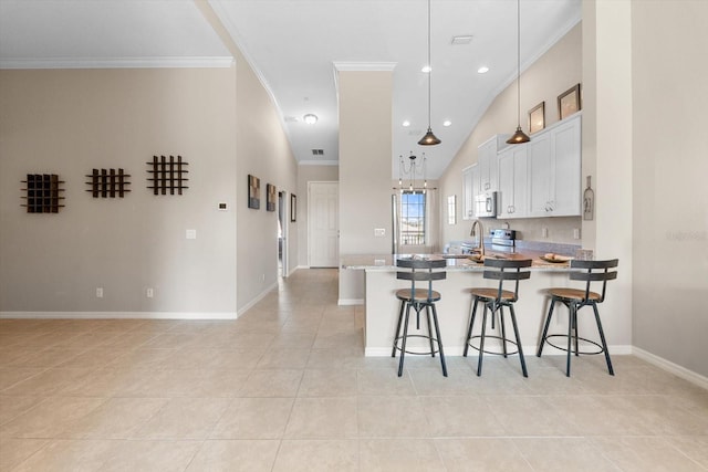 kitchen featuring a breakfast bar, light tile patterned floors, stainless steel appliances, ornamental molding, and a peninsula