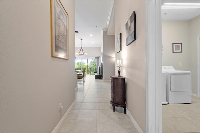 hall featuring washer / dryer, baseboards, light tile patterned floors, and a chandelier