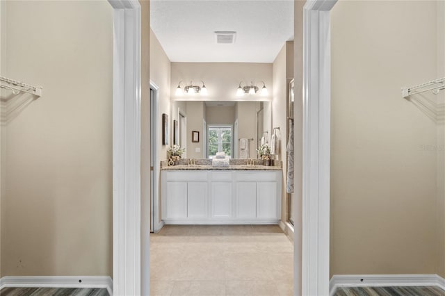 full bath featuring double vanity, visible vents, a stall shower, a sink, and baseboards