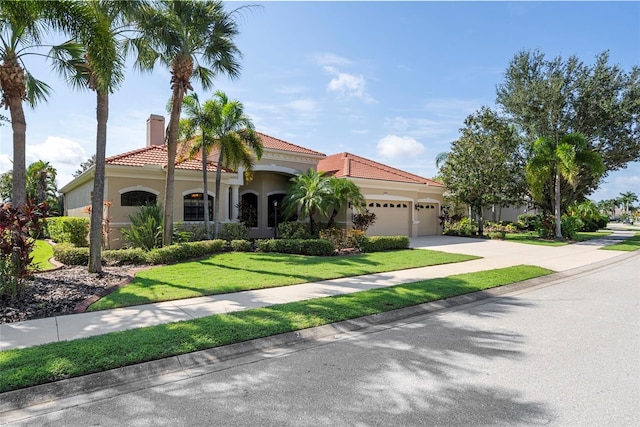 mediterranean / spanish-style home featuring a front lawn and a garage