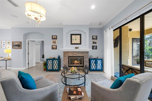 living room with a fireplace, light tile patterned floors, crown molding, and an inviting chandelier