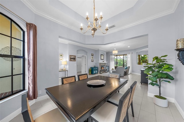 dining space featuring light tile patterned flooring, ornamental molding, and a tray ceiling