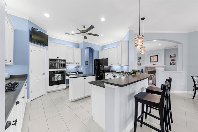 kitchen featuring a breakfast bar, crown molding, black appliances, decorative light fixtures, and white cabinetry