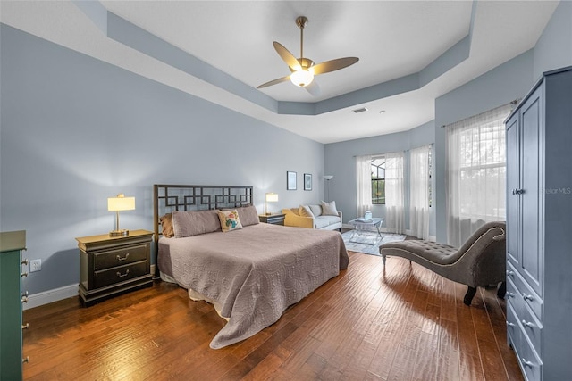 bedroom featuring ceiling fan, a raised ceiling, and dark wood-type flooring