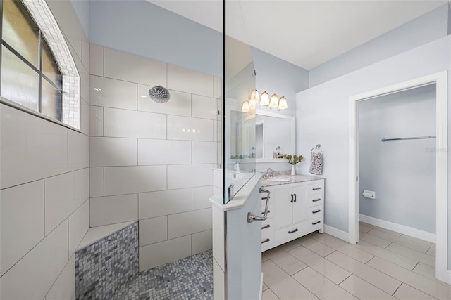 bathroom featuring a tile shower, tile patterned flooring, and vanity