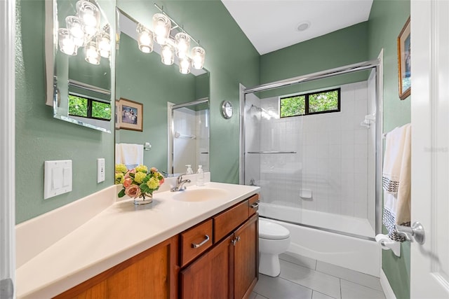 full bathroom with combined bath / shower with glass door, vanity, tile patterned flooring, and toilet