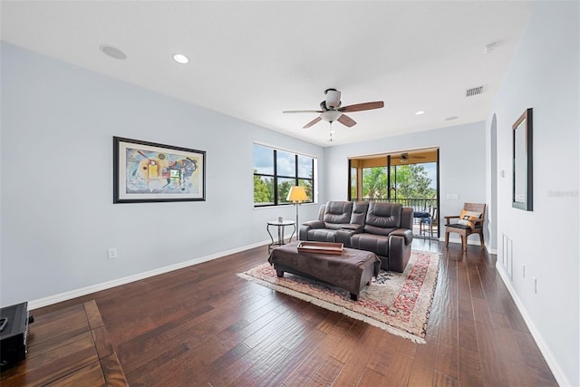 living room featuring ceiling fan and dark wood-type flooring