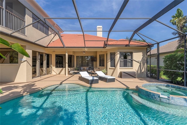 view of swimming pool featuring glass enclosure, an in ground hot tub, ceiling fan, and a patio