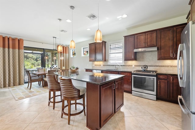 kitchen featuring a kitchen island, stainless steel appliances, a healthy amount of sunlight, and dark stone counters