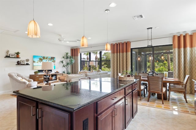 kitchen featuring pendant lighting, ceiling fan, dark stone countertops, and a center island