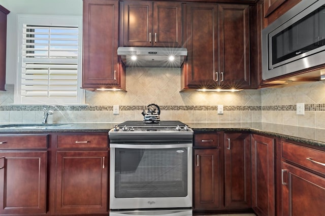 kitchen featuring dark stone countertops, appliances with stainless steel finishes, sink, and decorative backsplash