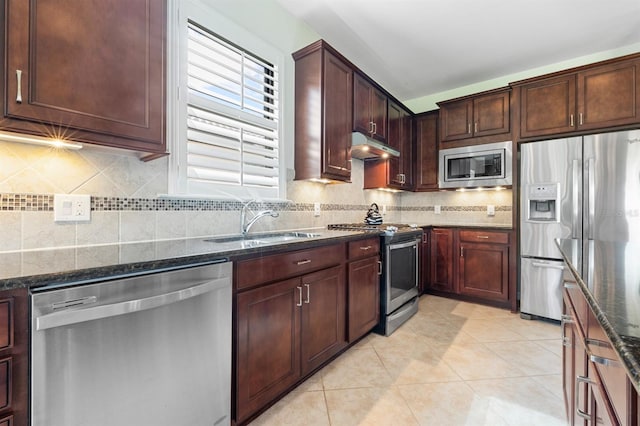 kitchen featuring appliances with stainless steel finishes, sink, decorative backsplash, dark stone countertops, and light tile patterned flooring