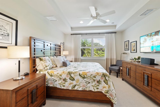 carpeted bedroom featuring a raised ceiling and ceiling fan