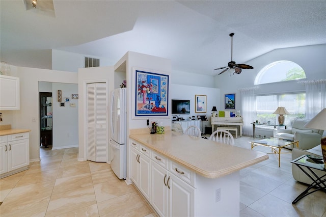 kitchen featuring vaulted ceiling, light tile patterned floors, white cabinetry, ceiling fan, and white refrigerator