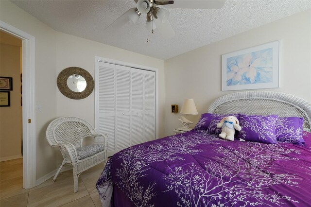 bedroom with a closet, ceiling fan, light tile patterned floors, and a textured ceiling