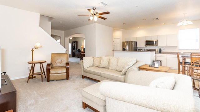 living room featuring light colored carpet and ceiling fan with notable chandelier