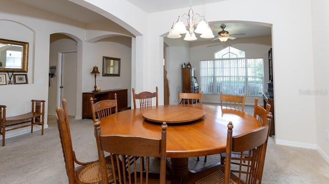 dining space with ceiling fan with notable chandelier and light colored carpet