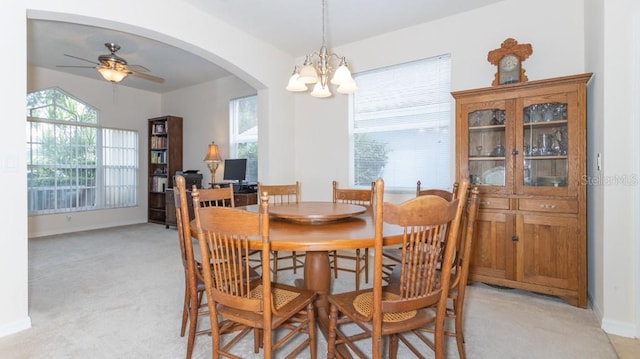 dining area with a healthy amount of sunlight, ceiling fan with notable chandelier, and light carpet