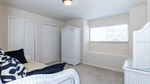 bedroom featuring multiple closets and light colored carpet