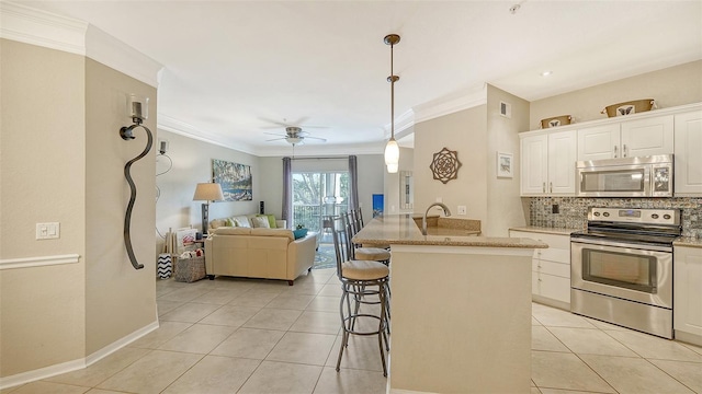 kitchen featuring appliances with stainless steel finishes, white cabinetry, ceiling fan, a kitchen breakfast bar, and pendant lighting