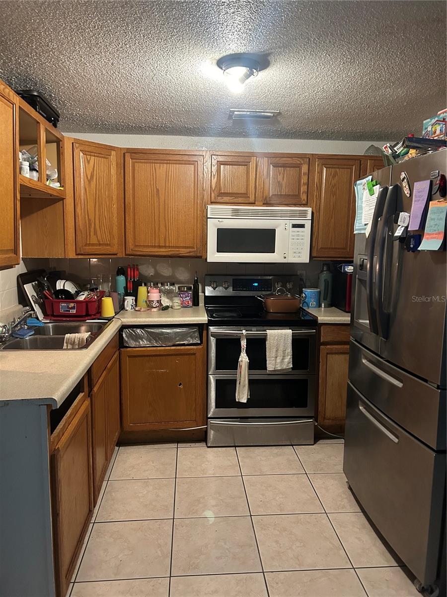 kitchen featuring a textured ceiling, stainless steel appliances, sink, and light tile patterned flooring