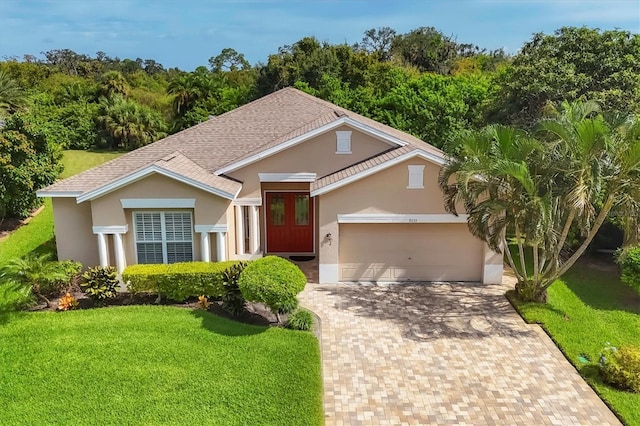view of front of house featuring stucco siding, decorative driveway, a shingled roof, an attached garage, and a front yard