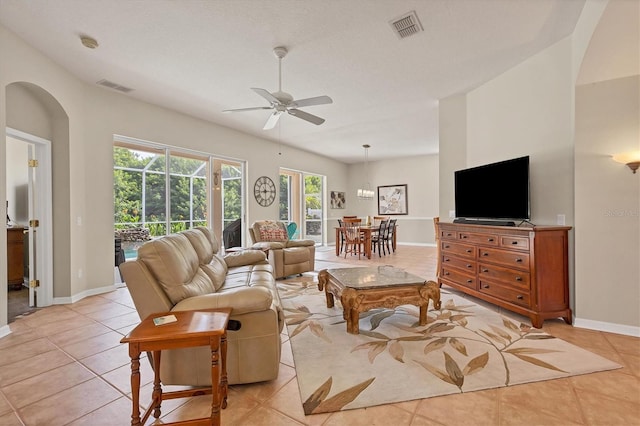 living room featuring a textured ceiling, light tile patterned floors, and ceiling fan