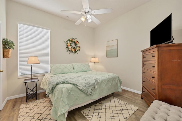 bedroom featuring ceiling fan, light wood-type flooring, and multiple windows