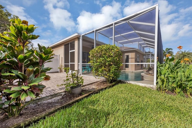 rear view of house featuring a lawn, a patio, and a lanai