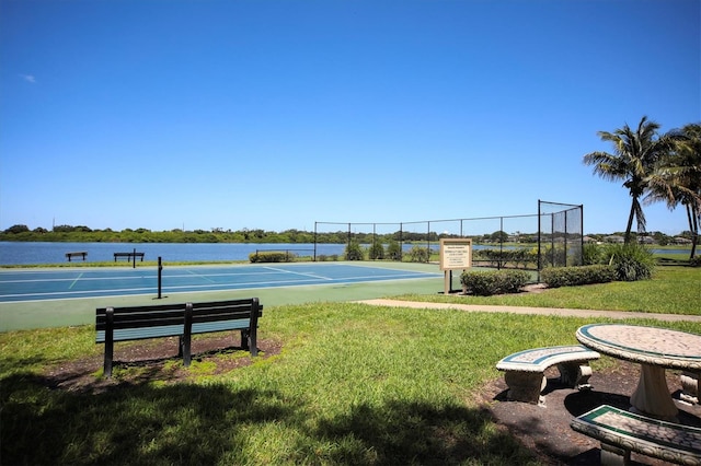 view of community featuring a water view, a yard, and tennis court