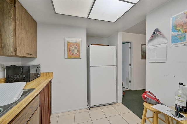 kitchen with light tile patterned flooring and white fridge