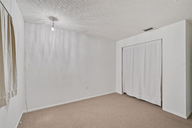 unfurnished bedroom featuring light carpet and a textured ceiling