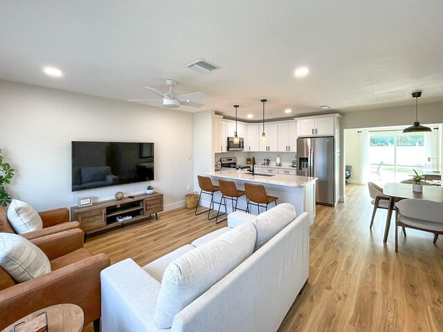 living room featuring ceiling fan and light hardwood / wood-style flooring