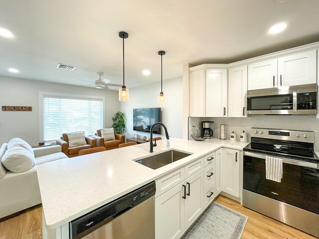 kitchen featuring appliances with stainless steel finishes, light hardwood / wood-style floors, sink, kitchen peninsula, and ceiling fan