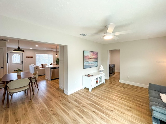 living room featuring light hardwood / wood-style flooring, ceiling fan, and washer and clothes dryer