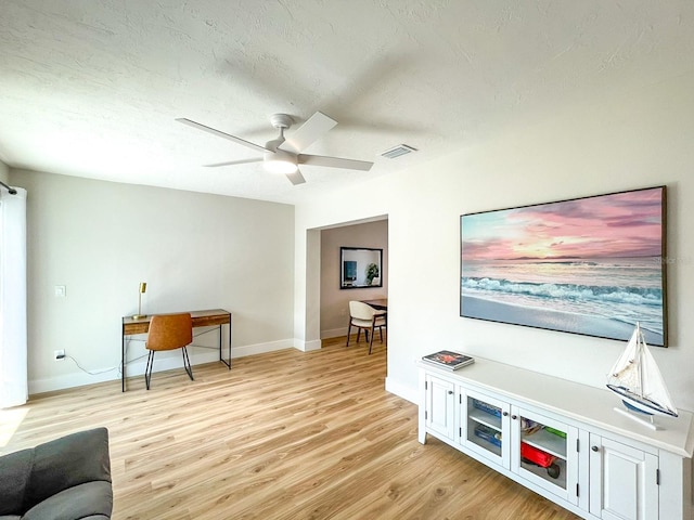 living room featuring a textured ceiling, ceiling fan, and light hardwood / wood-style floors