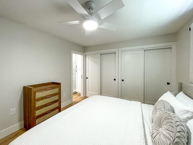 bedroom featuring light hardwood / wood-style flooring, two closets, and ceiling fan