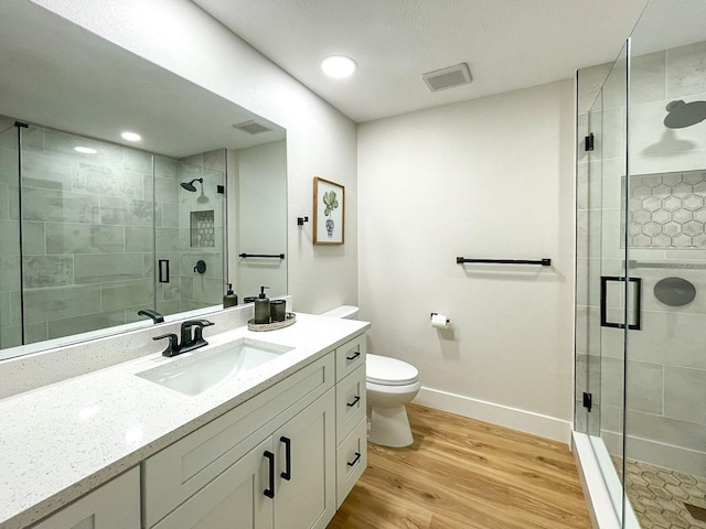 bathroom featuring a shower with shower door, toilet, hardwood / wood-style flooring, and vanity